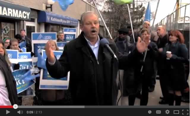 Smokey Thomas speaks at rally while OPSEU members hold up signs around him