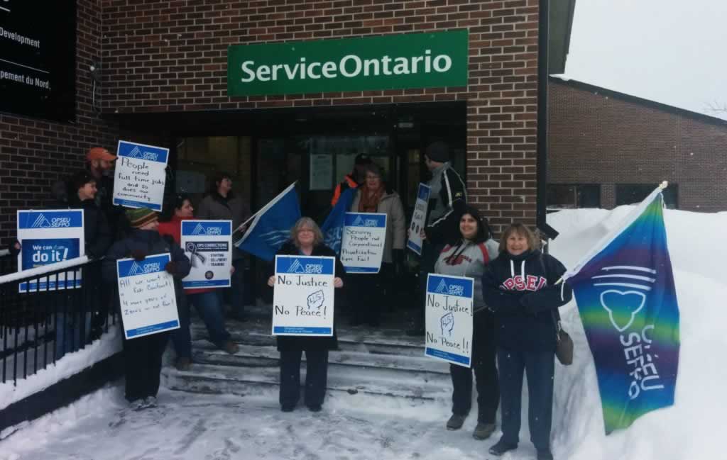 OPSEU members stand outside a Service Ontario with signs that say: No justice, No peace in Ignace