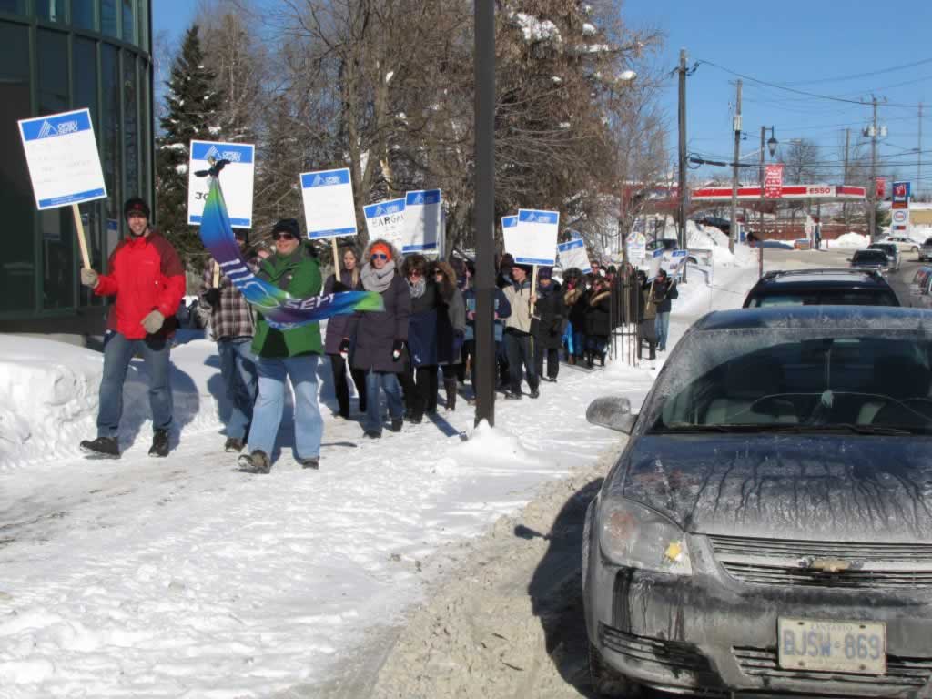 OPSEU members marching in a rally holding up flags and signs