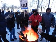 OPSEU members hold up signs and stand around a fire during protest