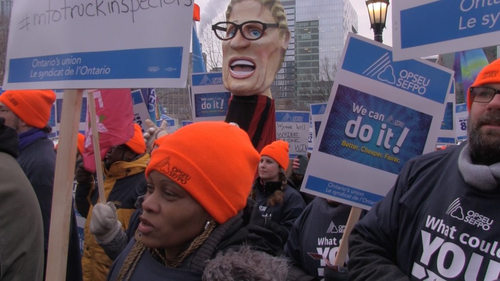 OPSEU members attend rally, holding up signs that say 'We can do it! Better, cheaper, fairer'
