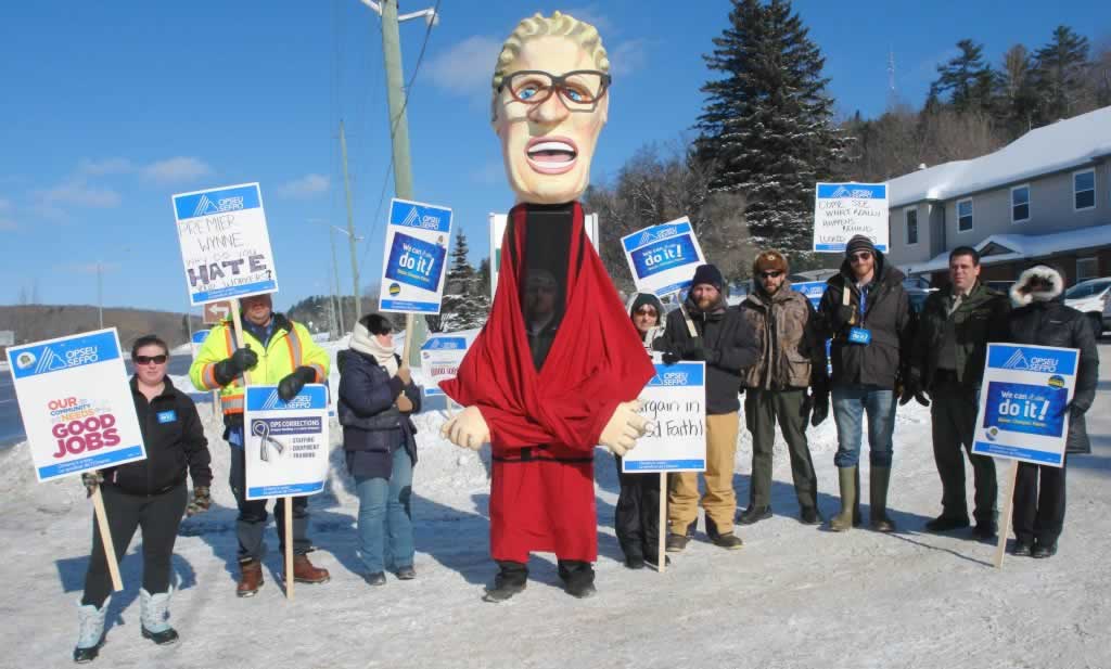 OPSEU members pose together holding signs next to Kathleen Wynne