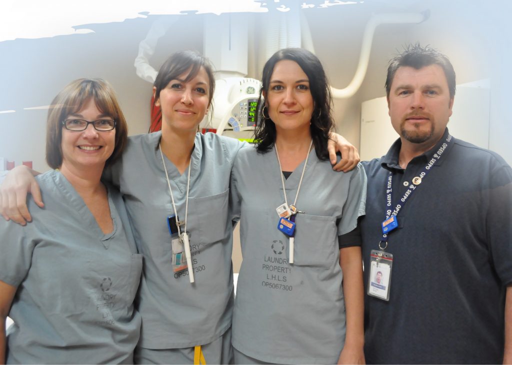 A group of 3 women in grey uniforms and a man in a dark blue polo shirt