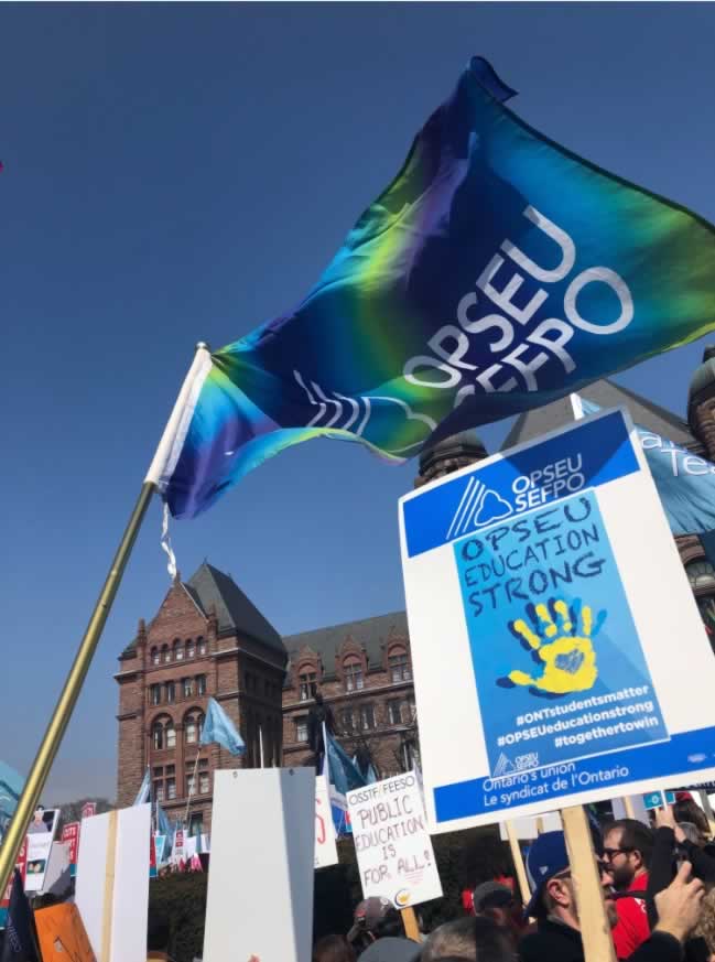OPSEU flag and sign over a large rally in front of Queen's park.