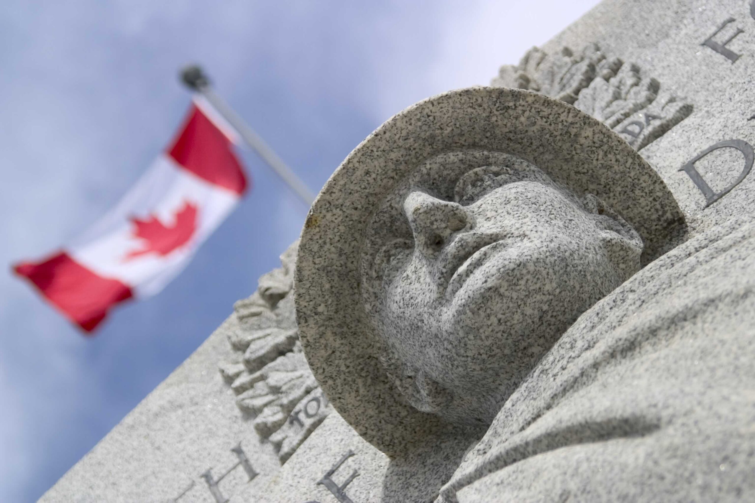 War memorial with Canadian flag in the background.