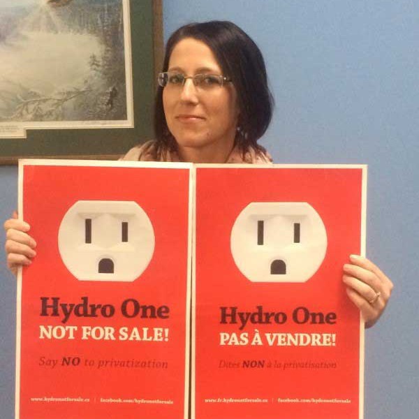We Own It member mobilizer Carole Gregorcic holding Hydro One Not For Sale signs