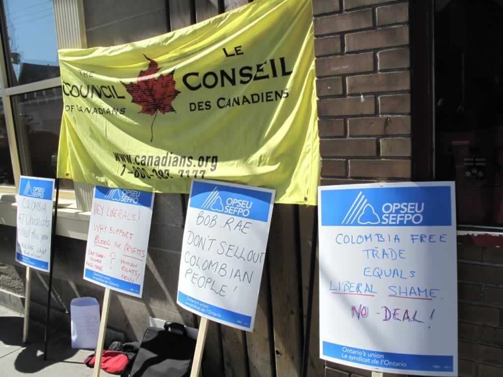 Four OPSEU picket signs with messages about Colombian free trade.