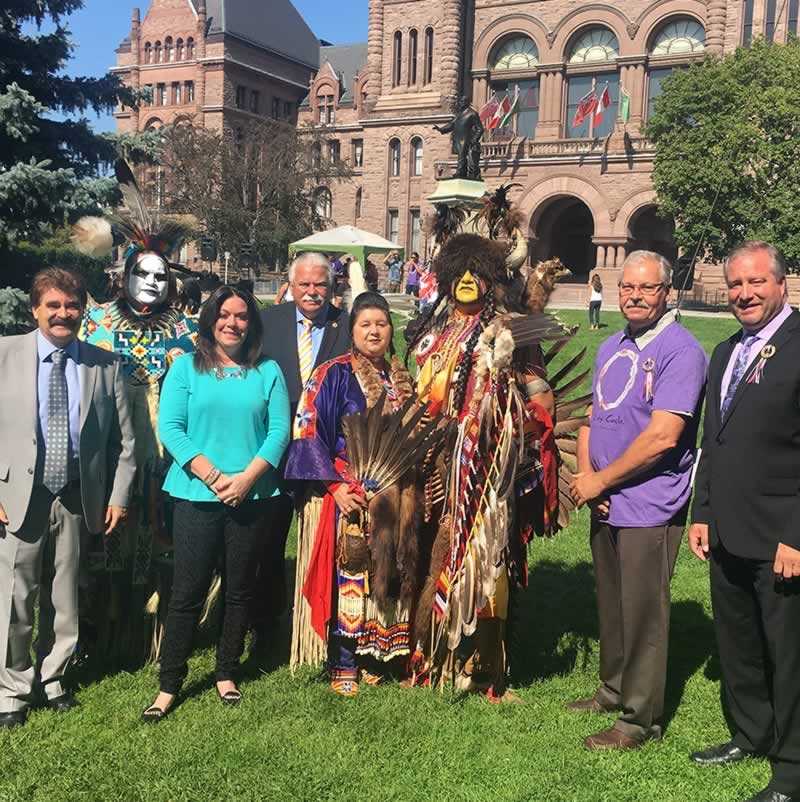 Warren (Smokey) Thomas standing with group in front of Queens Park during Pow Wow