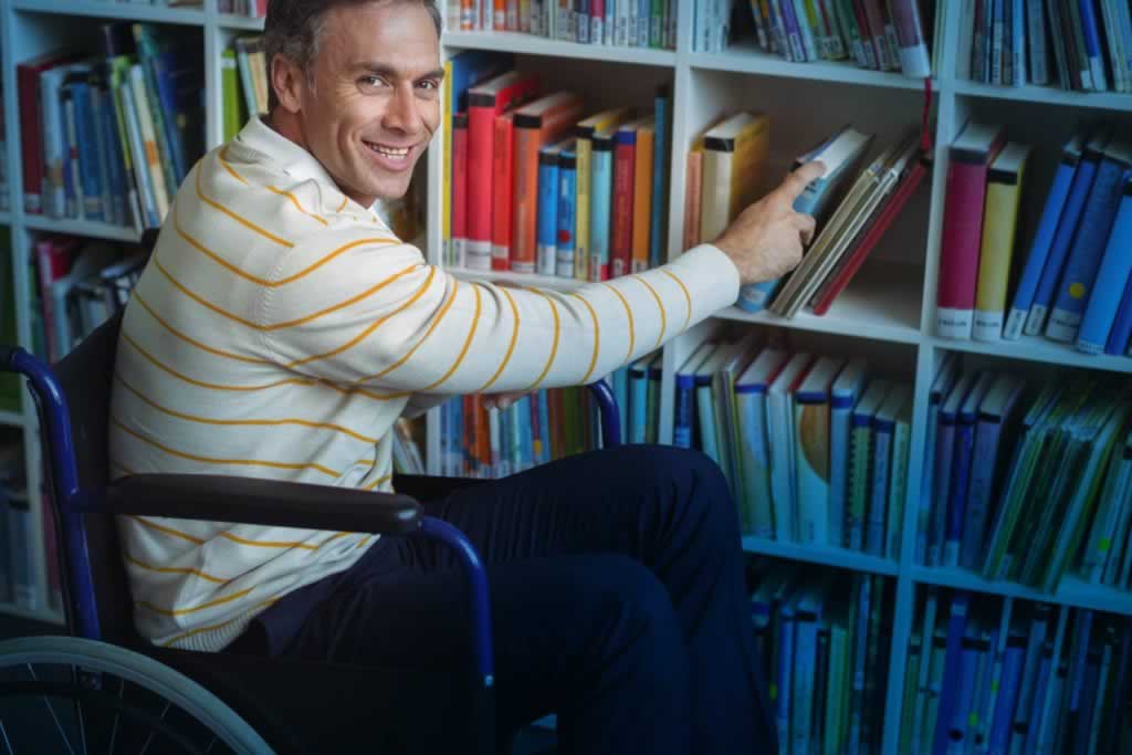 Professor holding books by bookshelf