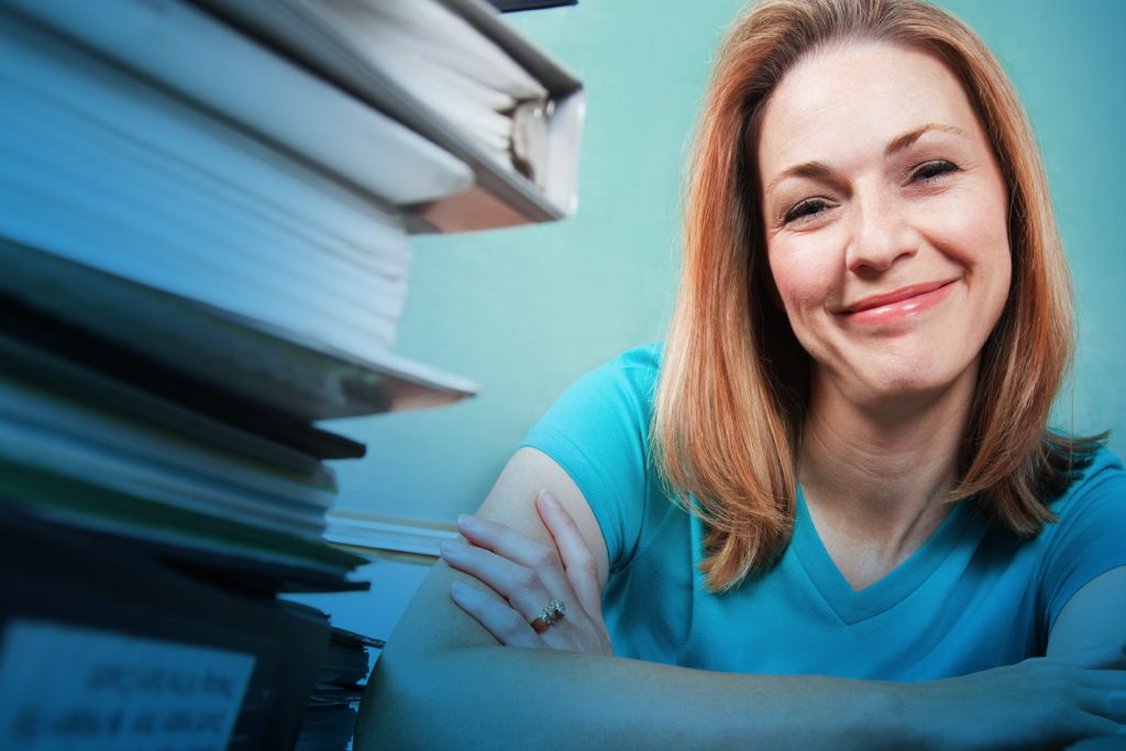 Woman smiling beside stack of books