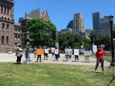 Members holding signs outside Queen's Park