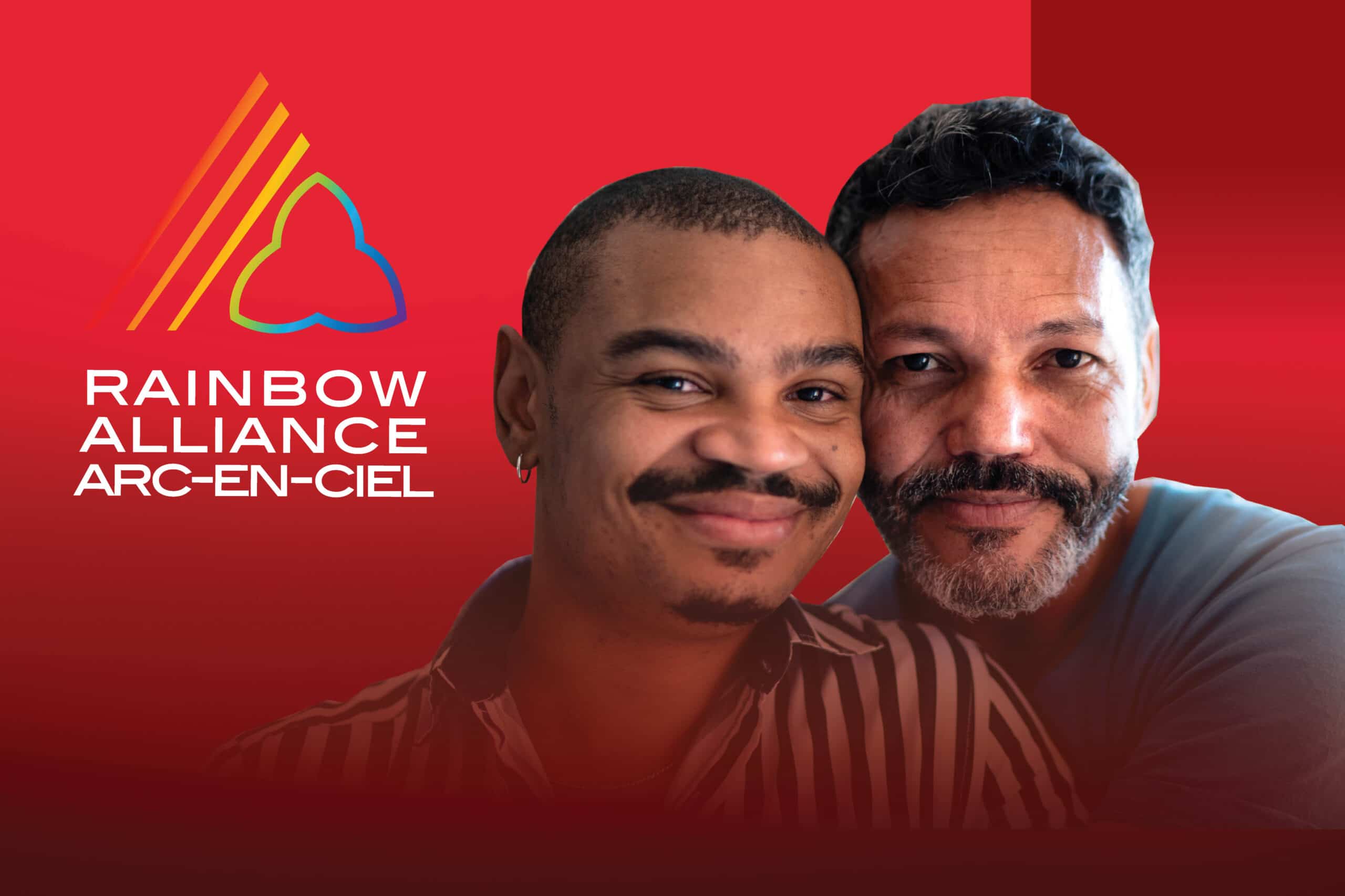 Two men close together smiling for the camera beside the Rainbow Alliance logo.