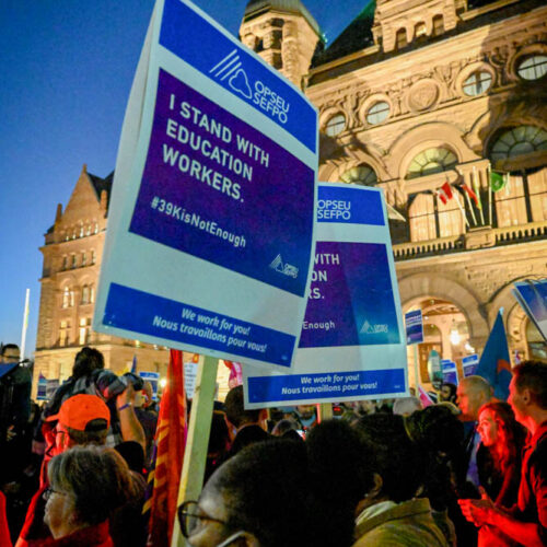 Picket sign that says 'I stand with education workers' in front of Queen's Park