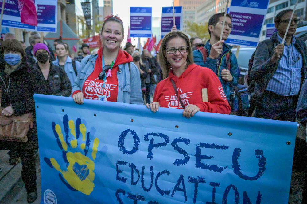 Workers at a rally, holding a banner 'OPSEU Education Strong'