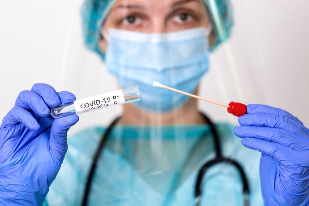 Health professional in mask and facemask holds a covid test