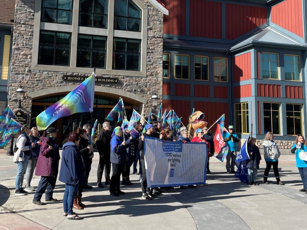 Crowd shot of rally holding large banner and many OPSEU/SEFPO flags