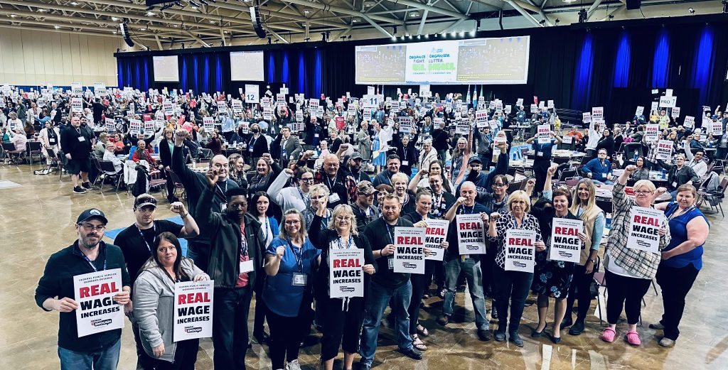 Convention members standing with "Real Wage Increases" signs