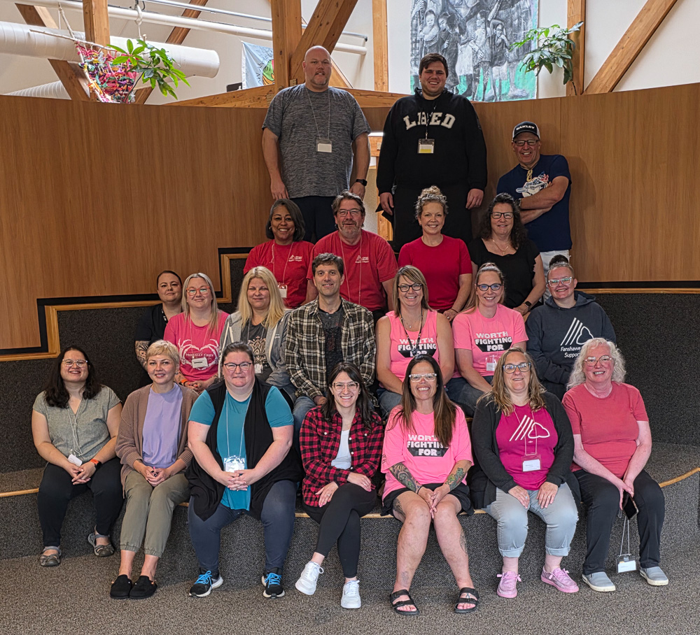 Roughly two dozen people smiling and posing together.