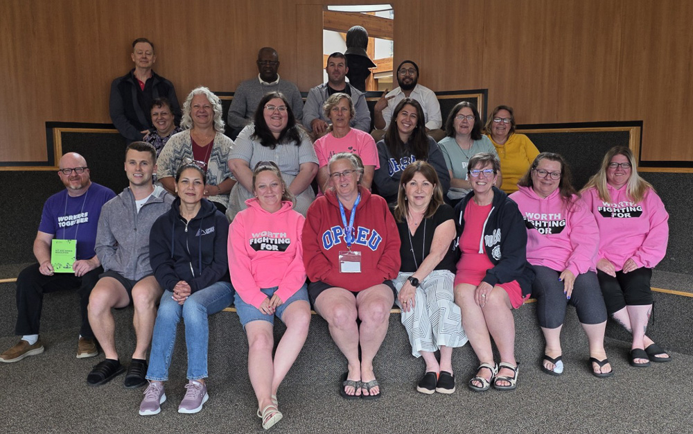 Roughly two dozen people smiling and posing together.