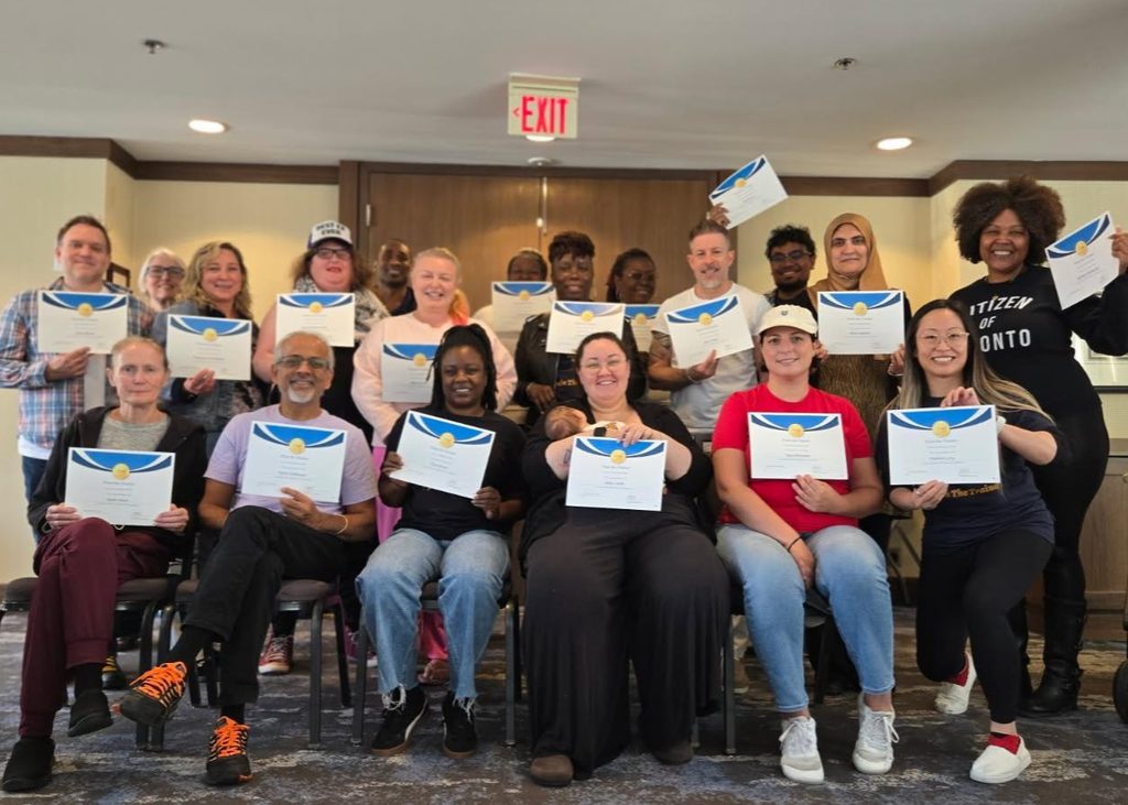 Group picture of people standing and sitting together holding certificates.