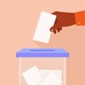 The hand of a person putting a ballot into a ballot box