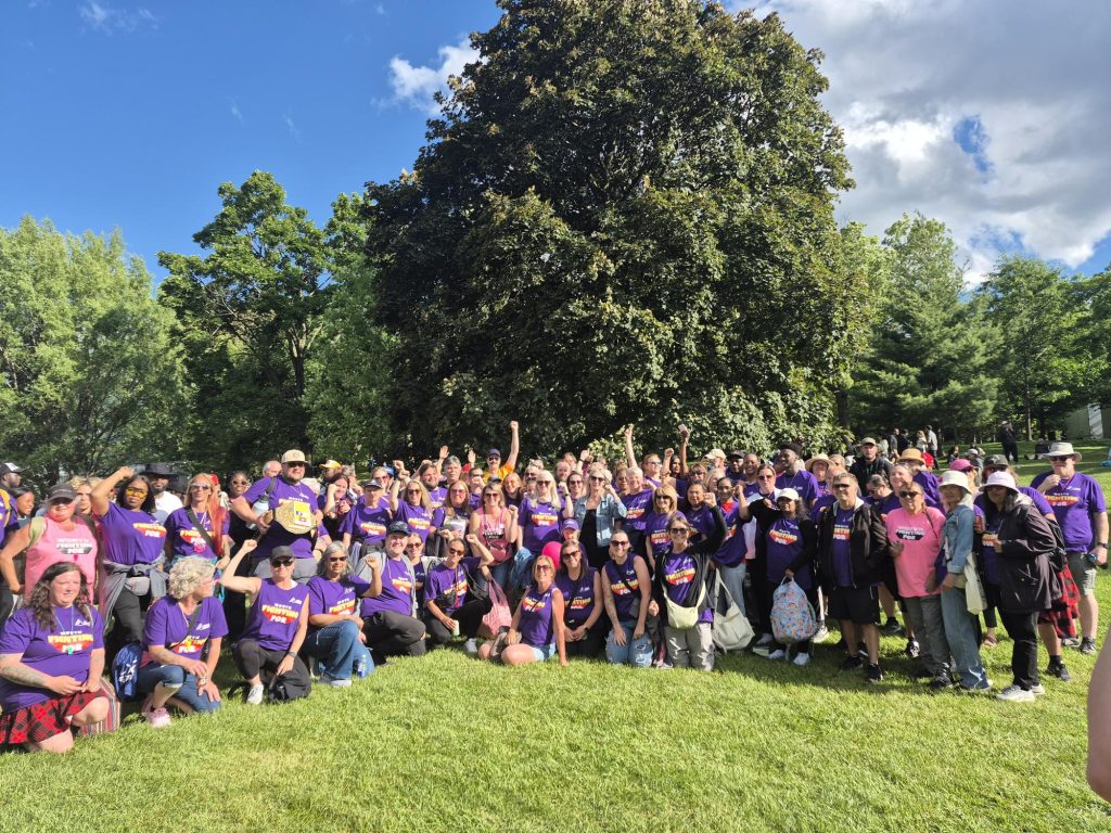 Workers in matching purple shirts posing outside at Ford Fest.